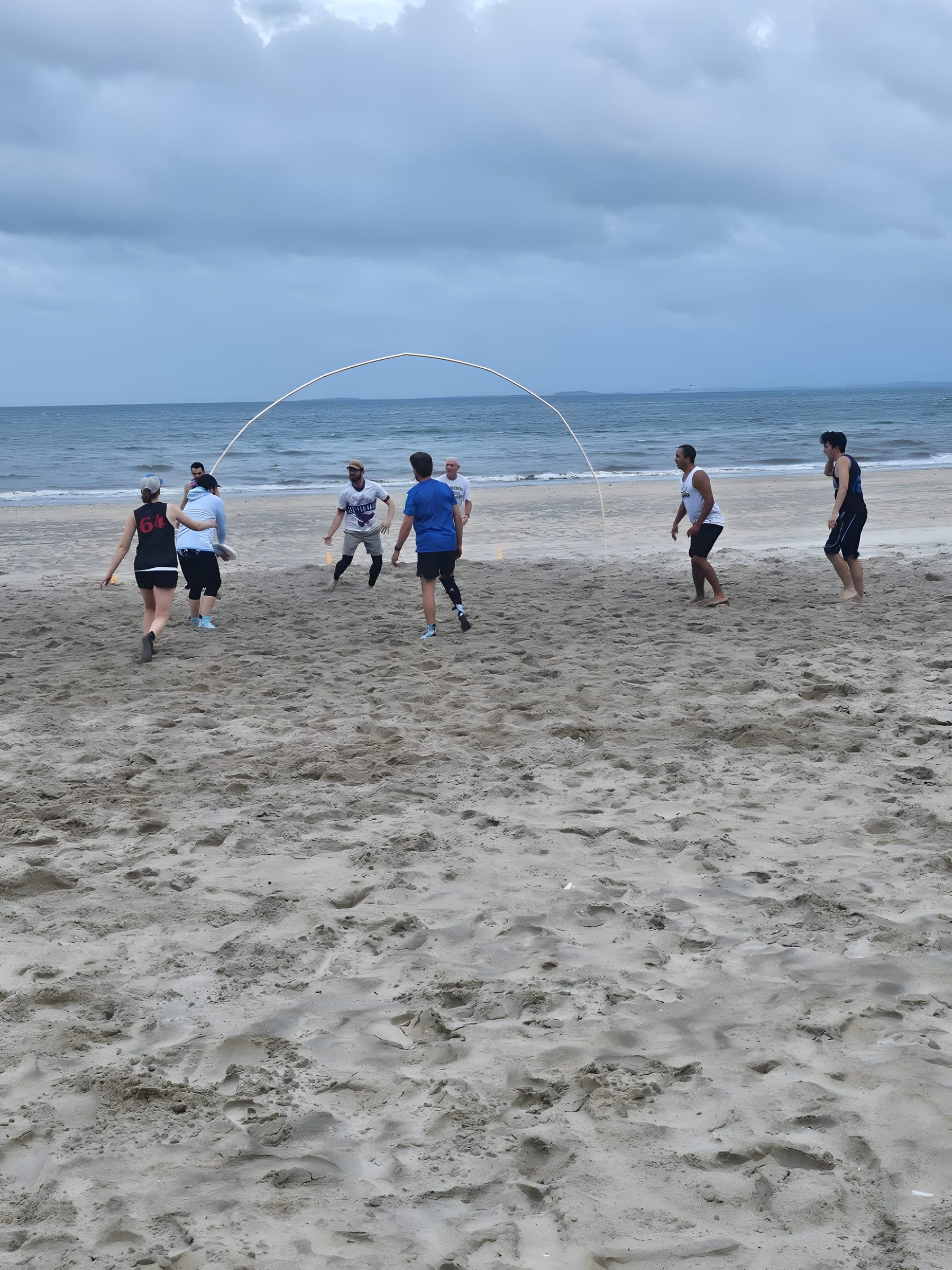 Beach goaltimate at Revere — players around the curved goal hoop on the sand