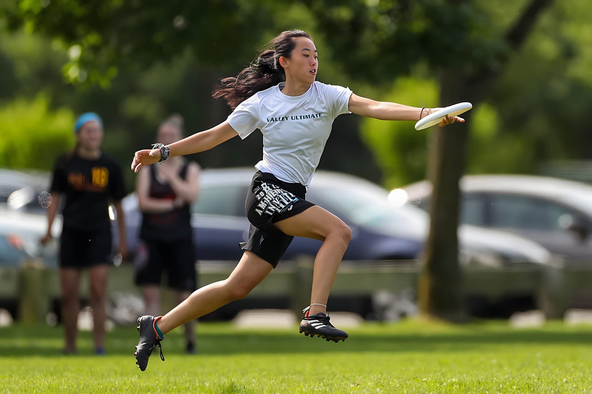 A youth player fully airborne, reaching out to catch a disc one-handed at a summer tournament